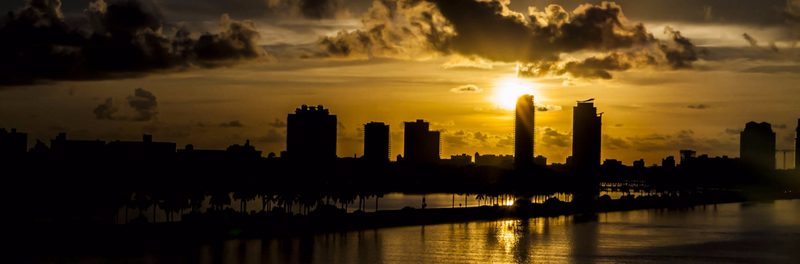 City skyline in silhouette against a golden sunset over water