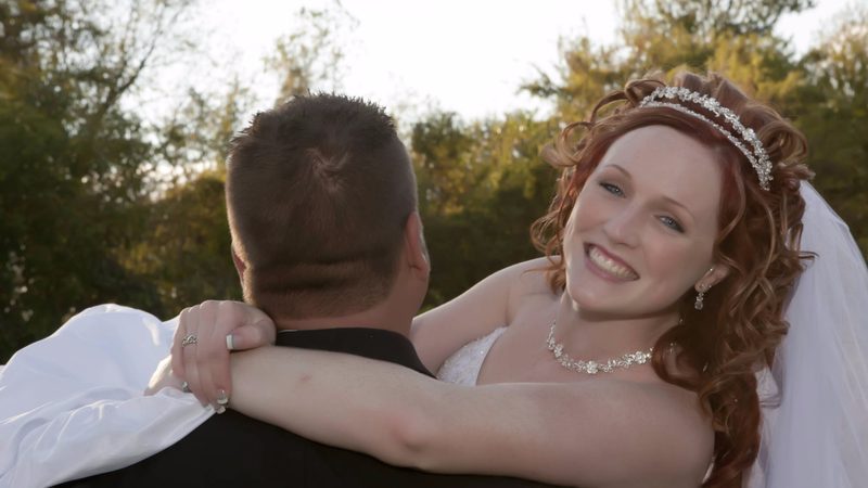 Bride smiling over the groom's shoulder at sunset